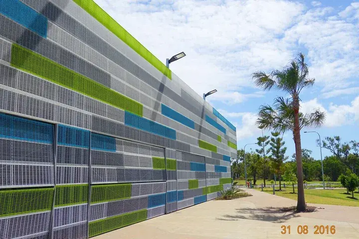 Coloured aluminium louvre and sunscreen wall along a landscaped walkway